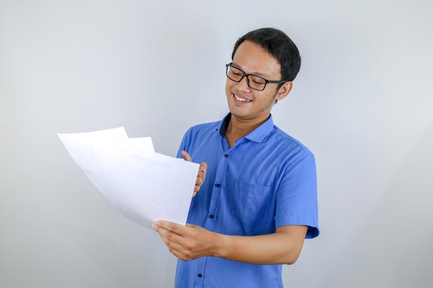 Young Asian Man is smile and happy when looking on paper document Indonesian man wearing blue shirt