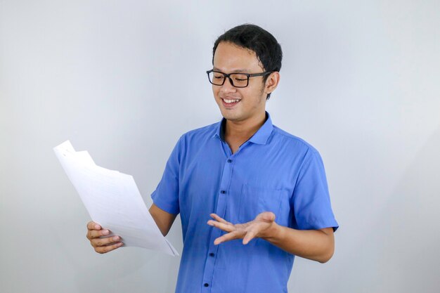 Young Asian Man is smile and happy when looking on paper document Indonesian man wearing blue shirt