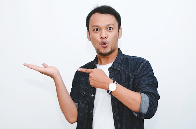 Young asian man is surprised and shouting wow with pointing right with his hand isolated on gray background