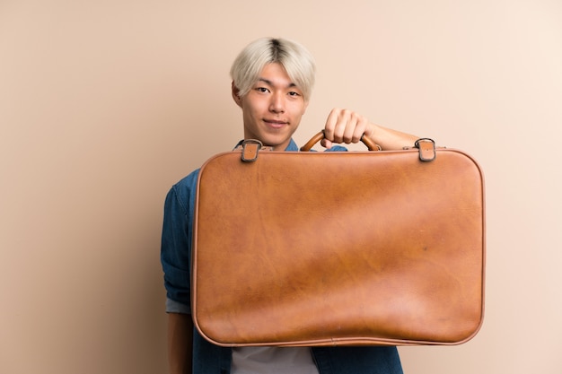 Young asian man over isolated  holding a vintage briefcase