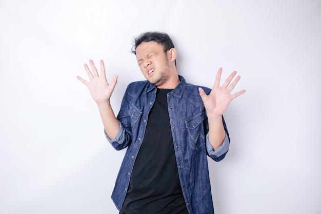 Young Asian man isolated on white background face covered by fingers frightened and nervous