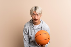 Young asian man over isolated  with ball of basketball