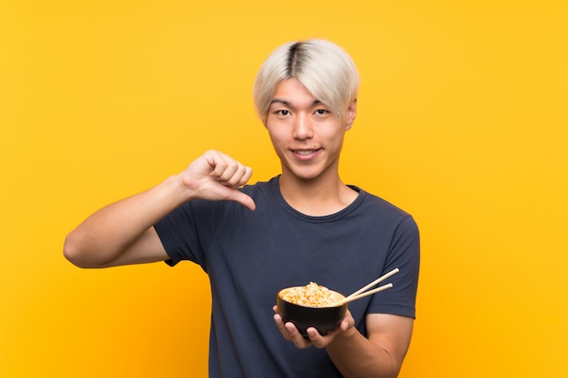 Young asian man over isolated yellow  proud and self-satisfied