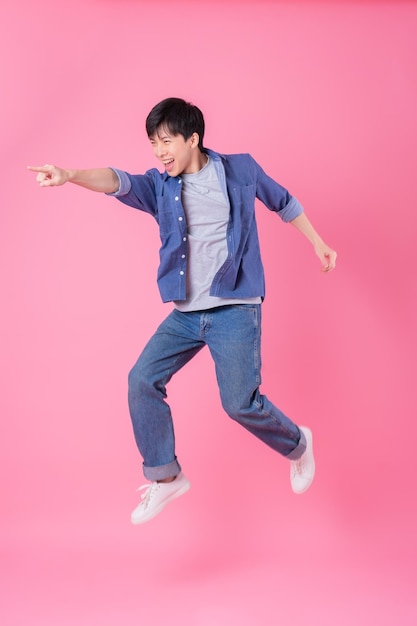 青い背景にジャンプする若いアジア人男性