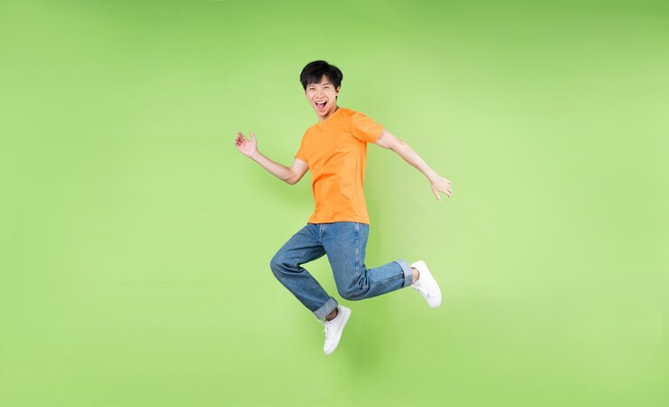 Photo 若いアジア人のジャンプ、緑の背景に分離
