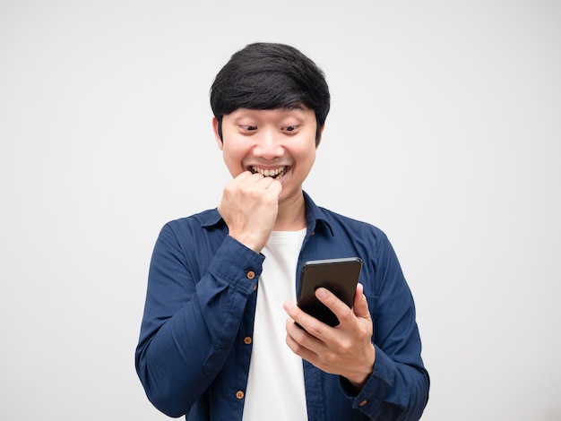 Young asian man looking at mobile phone in his hand feeling excited