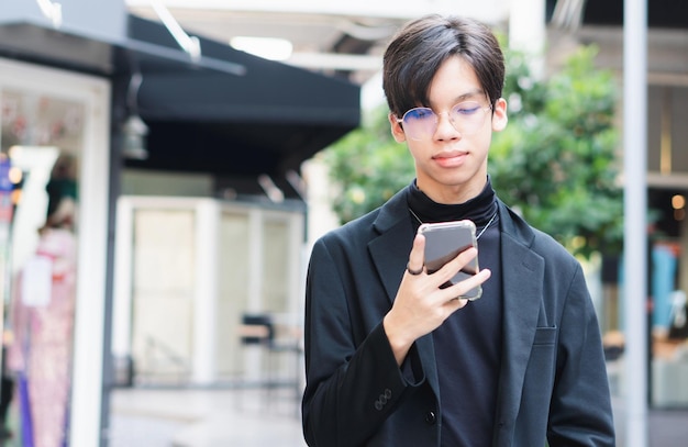 スマートフォンのディスプレイを見ている若いアジア人男性smsを入力する眼鏡をかけた少年