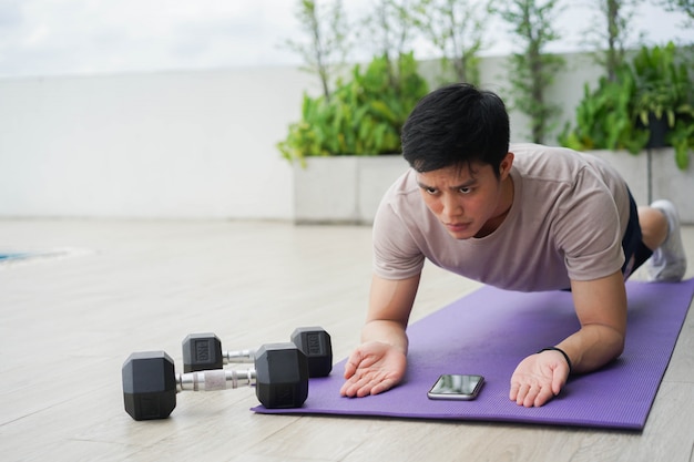 young asian man plank exercise on mat to built strength core muscle