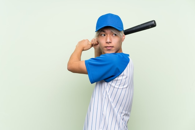 Young asian man playing baseball over isolated green