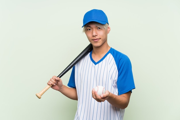 Young asian man playing baseball over isolated green 