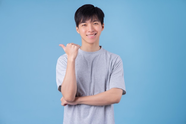 Young Asian man posing on blue background