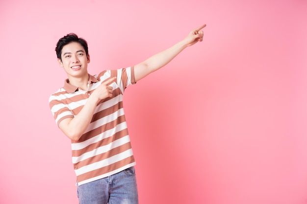 Молодой азиатский мужчина позирует на розовом фоне