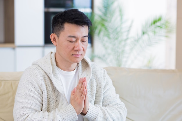 一人で家で祈る若いアジア人