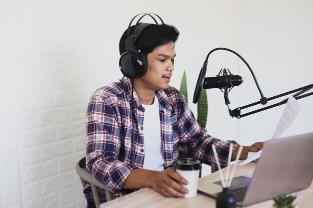 Young asian man radio host reading brief content during podcast