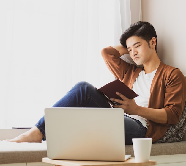 집에서 휴식을 취하면서 책을 읽는 젊은 아시아 남자