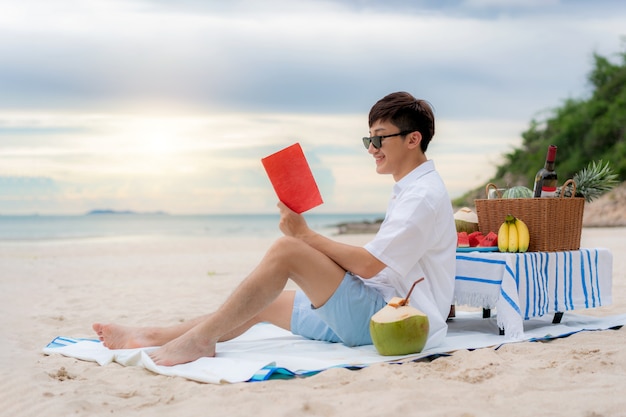 Young Asian man reading a book on the beach