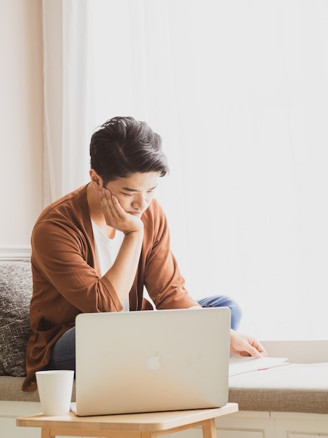 Young asian man reading a book while relaxing at home