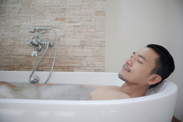 젊은 아시아 남자 휴식과 욕조에서 스파.