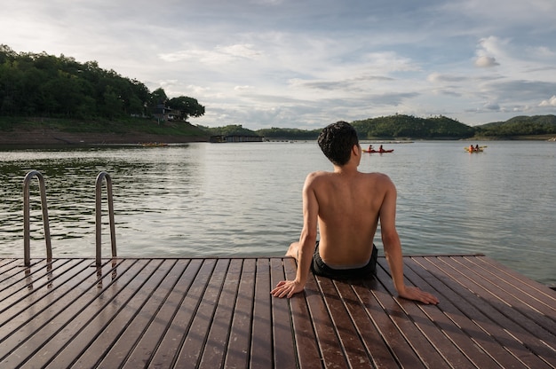 Young asian man relaxing on lakeside at evening