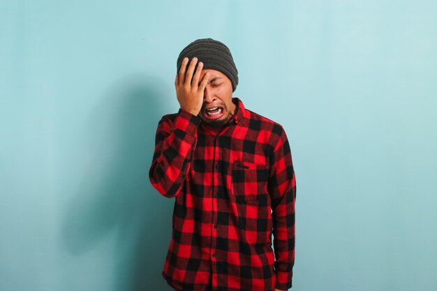 Photo young asian man rubbing his swollen eyes due to dust allergy and itching isolated on blue background