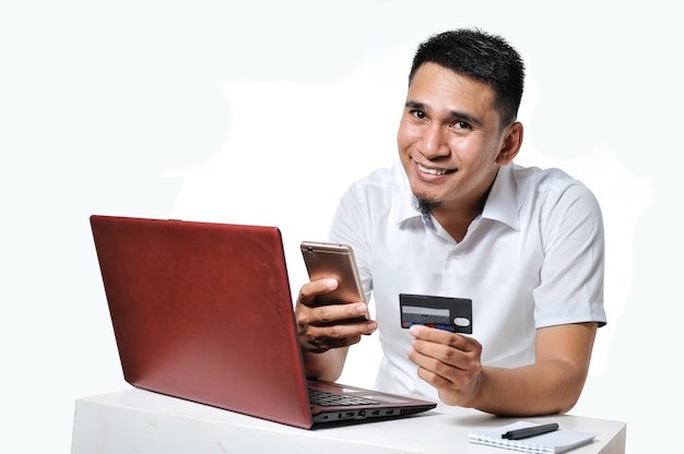 Young Asian man shopping online using debit card to pay it, isolated on white background