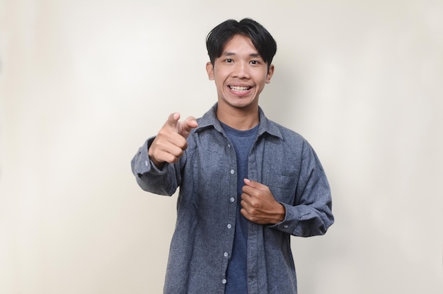 Young Asian man showing excited expression while pointing ahead