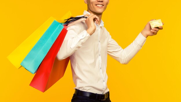 Young asian man showing his shopping bag and credit card