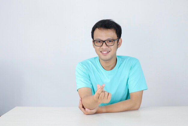 파란색 셔츠를 입고 고립 된 흰색 배경 인도네시아 남자와 사랑 한국 기호를 보여주는 젊은 아시아 남자