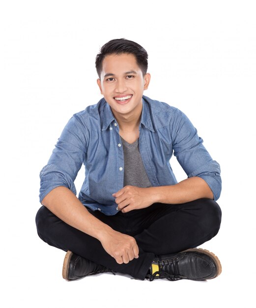 Young asian man sitting on the floor, smiling