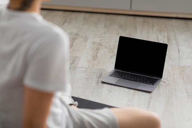 Photo young asian man sitting on mat with blank pc mockup