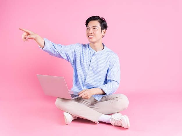 Young Asian man sitting and using laptop on background