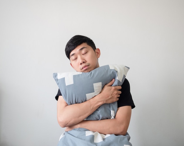 Young Asian man sleep and hugging pillow on white isolated background,Sleepy man concept