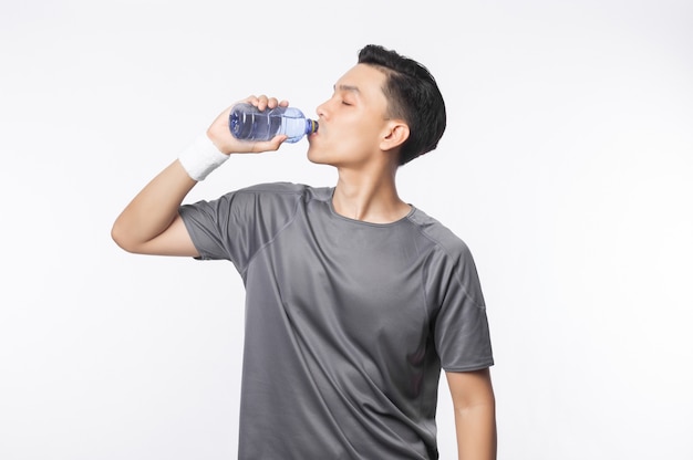 Young asian man in sport outfits drinking water with happy face isolated 