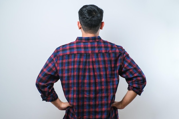 Young asian man standing backwards looking away with arms on body