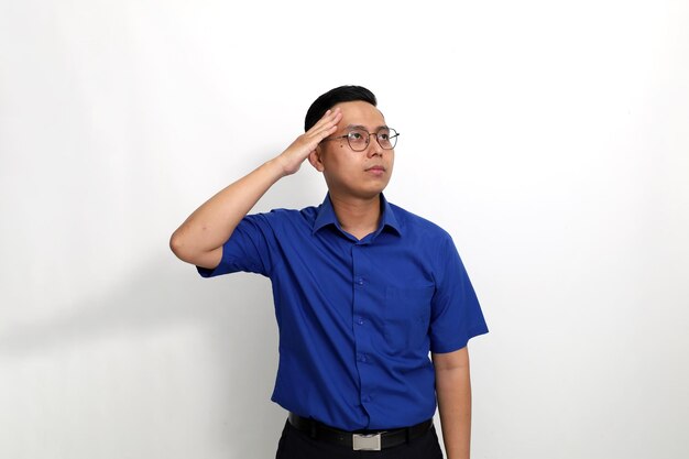 Young asian man standing with salute hand gesture and looking sideways isolated on white