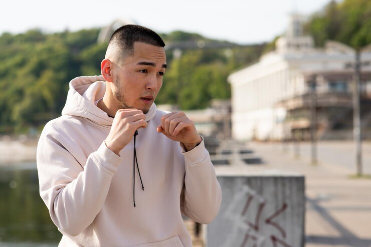 Photo アジアの若い男性が水辺に立って、聖霊降臨祭の服を着た若い男が彼の前に拳を握ります