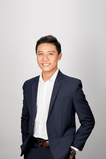 Photo a young asian man in suit put both hands in his pants pocket isolated on a white background