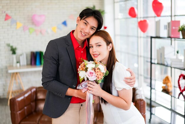 Photo a young asian man surprised his girlfriend by giving her rose and flower bouquet for her anniversary