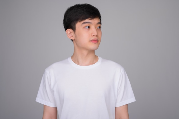 young Asian man thinking while looking away
