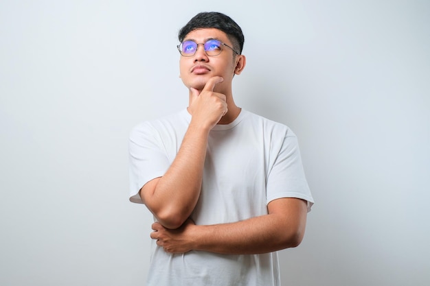 Young asian man thinking worried about a question concerned and nervous with hand on chin