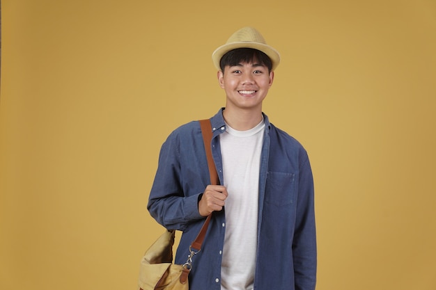 Young asian man traveler smiling isolated on yellow.