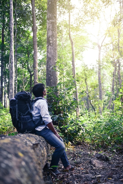 写真 タイの山で写真を撮るバックパックを持つ若いアジア人男性旅行者。