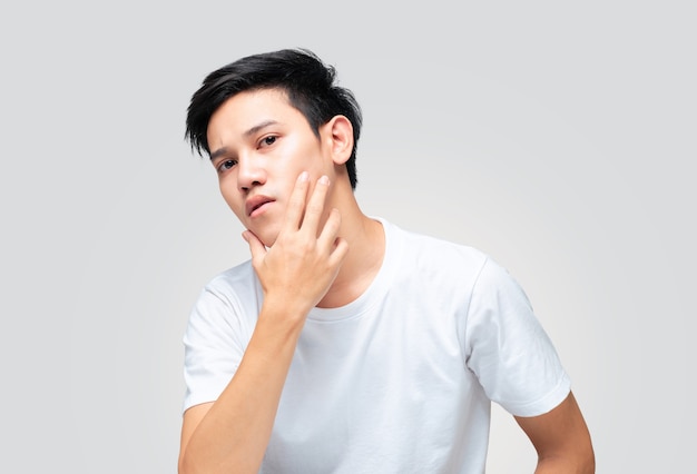 Photo young asian man using hand touches his chin to check his skin