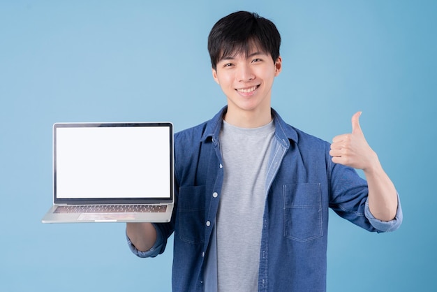 Young Asian man using laptop on blue background