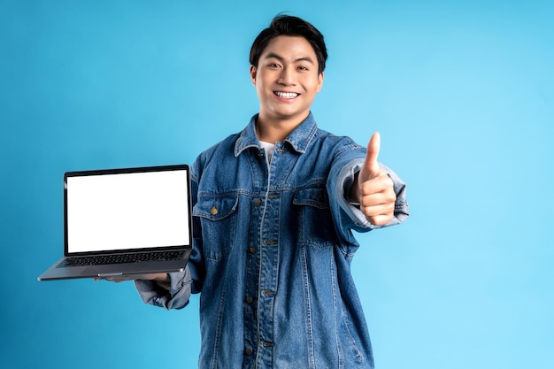 Young asian man using laptop on a blue background