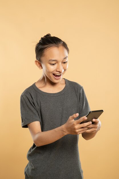 Молодой азиатский человек с помощью мобильного телефона в студии