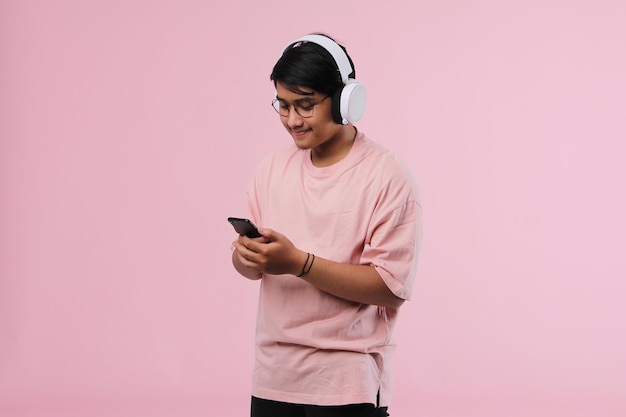 Young asian man using mobile phone while listening to music