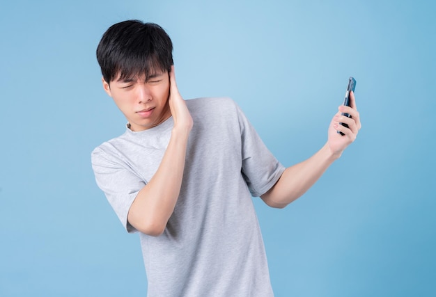 青の背景にスマートフォンを使用して若いアジア人