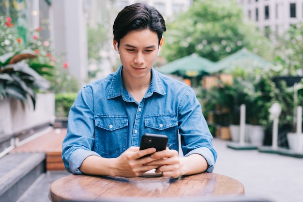 Young Asian man using smartphone at coffee shop