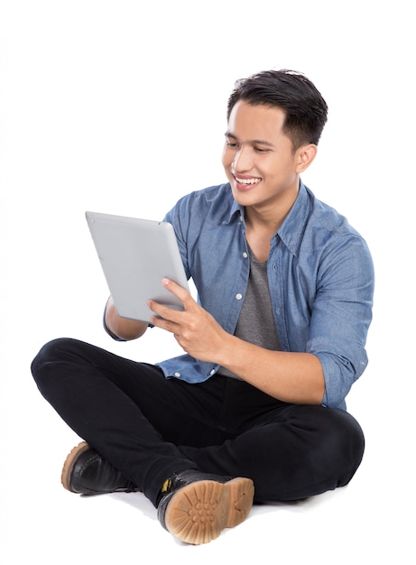 Young asian man using tablet pc while sitting on the floor